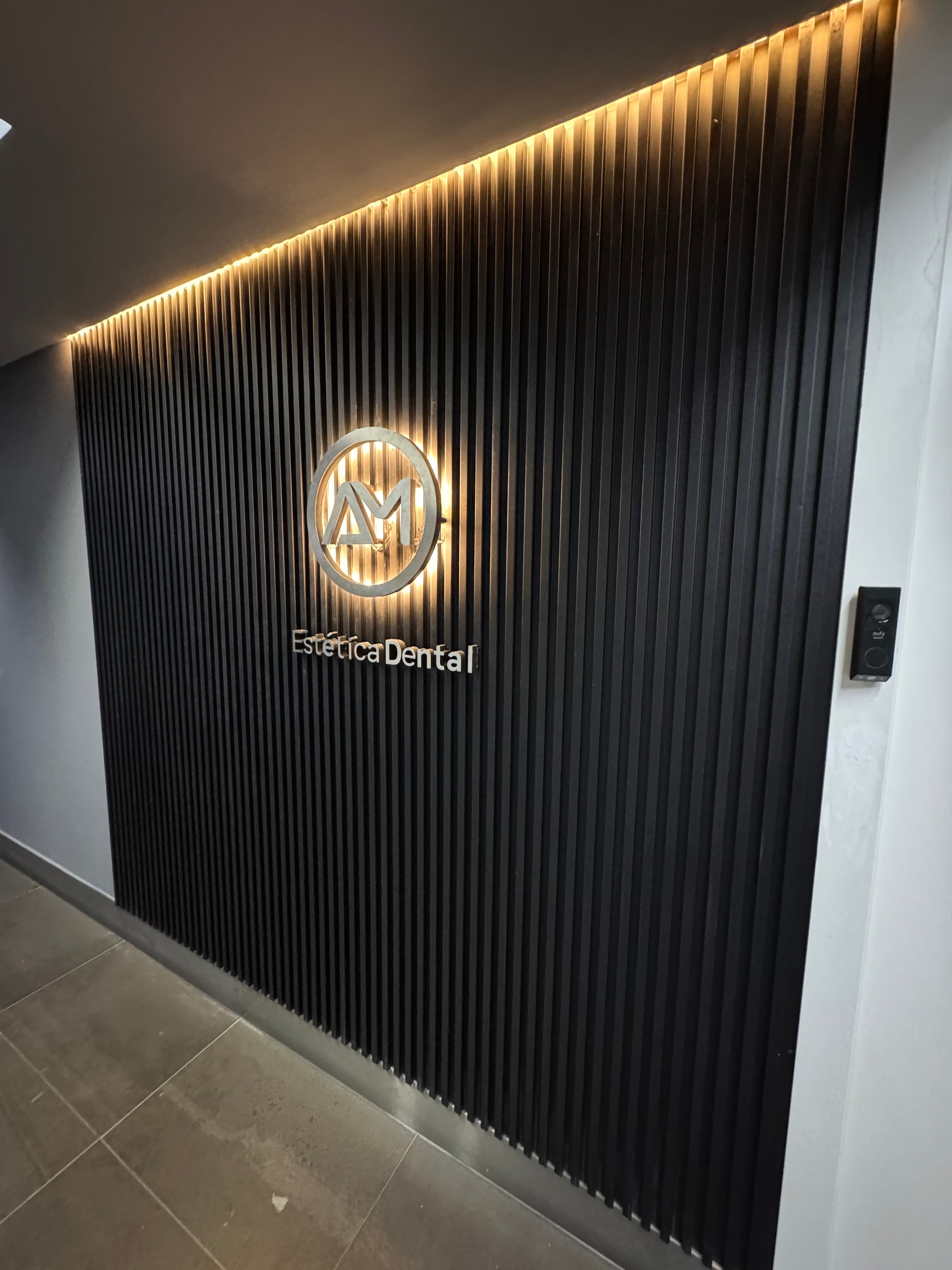 Entrada principal de AM Estética Dental con el logotipo iluminado en Puerto Madero