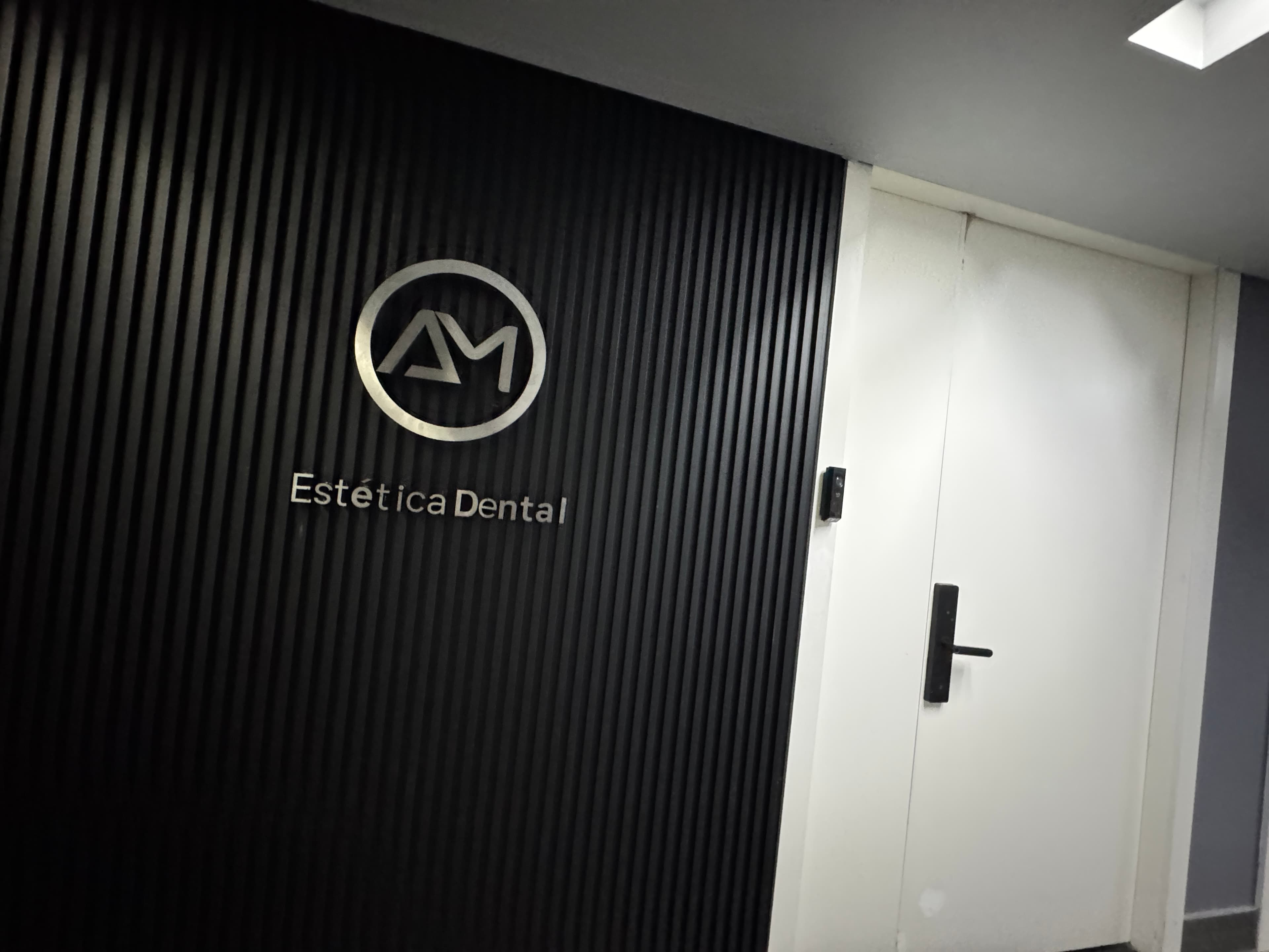 Letrero comercial de AM Estética Dental en la entrada exterior en Puerto Madero